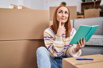 Young caucasian woman reading book with doubt expression at new home