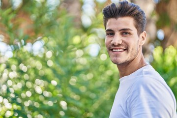 Naklejka na ściany i meble Young hispanic man smiling confident standing at park