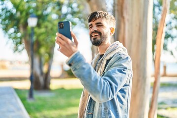 Young hispanic man smiling confident having video call at park