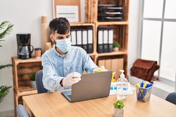 Young hispanic man business worker cleaning laptop at office