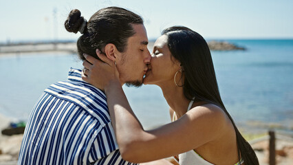 Man and woman couple sitting on bench kissing at seaside