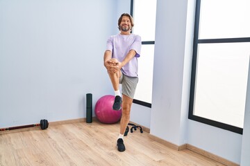 Middle age man smiling confident stretching leg at sport center