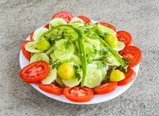 green fresh salad with tomato, cucumber, lemon served in plate isolated on grey background top view of pakistani and indian spices food