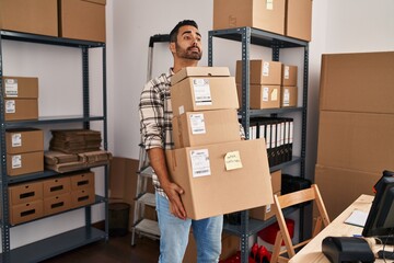 Young hispanic man ecommerce business worker holding packages at office