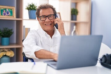 Middle age man talking on smartphone sitting on wheelchair teleworking at home