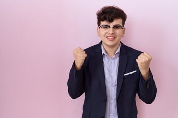 Young non binary man with beard wearing suit and tie celebrating surprised and amazed for success with arms raised and open eyes. winner concept.