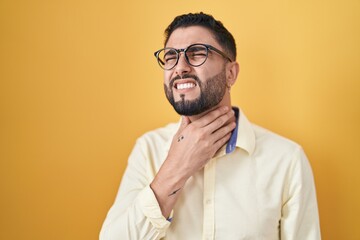Hispanic young man wearing business clothes and glasses touching painful neck, sore throat for flu, clod and infection