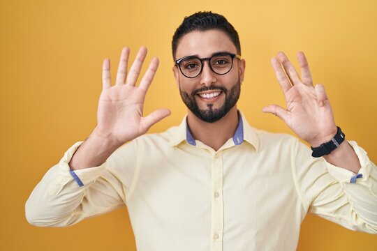 Hispanic young man wearing business clothes and glasses showing and pointing up with fingers number nine while smiling confident and happy.