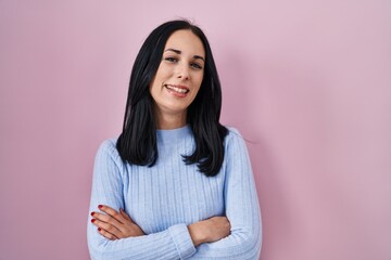 Fototapeta premium Hispanic woman standing over pink background happy face smiling with crossed arms looking at the camera. positive person.