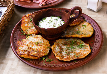 potato pancakes with sour cream and herbs on white plate