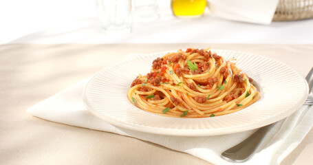 Spaghetti Bolognese on a white plate. Italian Pasta with meat tomato sauce on a light background. Dish of Mediterranean cuisine. Food on the table on a sunny day. Slow motion. Smooth movement. Zoom.