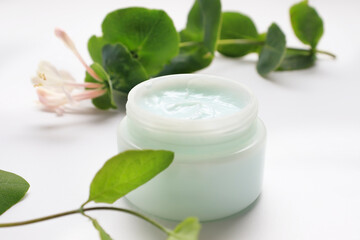 Hand or face cream in a jar next to a tropical plant. The concept of care cosmetics, anti-aging moisturizer