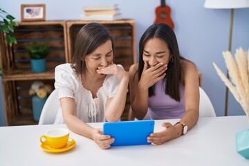 Two women mother and daughter watching video on touchpad at home