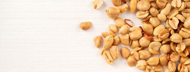 Spicy flavored peanut kernel spilling on white table background.