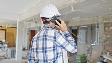 Middle age man builder talking on smartphone at construction site