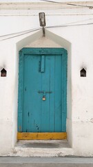 An old blue door, living in silence as a colourful remnant of the good times past.