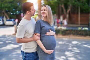Fototapeta premium Man and woman couple hugging each other expecting baby at street