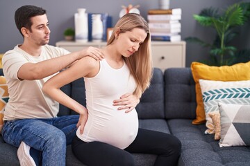 Man and woman couple expecting baby massaging back at home