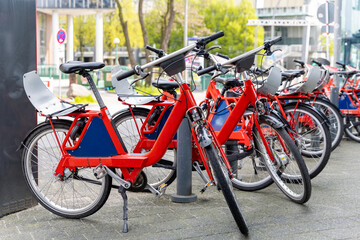 Fototapeta na wymiar Closeup view many red city bikes parked in row at german Hamburg city street rental parking sharing station or sale. Healthy ecology urban transportation. Sport environmental transport infrastructure