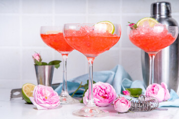 Frozen rose daiquiri or margarita cocktail, champagne, pink rose wine alcohol drink with roses flowers and lime slices