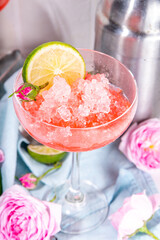 Frozen rose daiquiri or margarita cocktail, champagne, pink rose wine alcohol drink with roses flowers and lime slices
