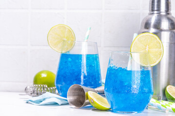 Iced blue curacao cocktail, drunken mermaid alcohol cocktail drink with lime slice garnish and...