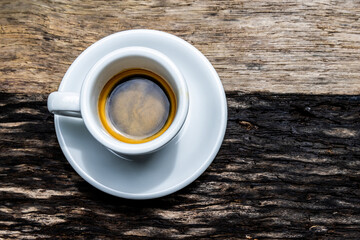 White cup of espresso on wooden background.