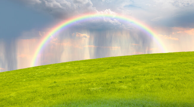 Beautiful landscape view of green grass field with rainbow - Aerial view of rain above countryside rural field or meadow landscape