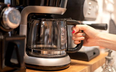 Females hand uses a coffee machine to boil the coffee and prepare and serve it to their customer.