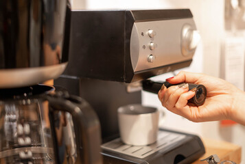 Females hand uses a coffee machine to boil the coffee and prepare and serve it to their customer.