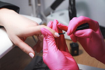 Nail technician does manicure for female client.