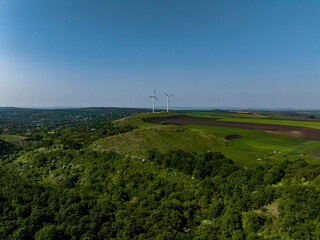 Fototapeta na wymiar two wind turbines on top of a hill with green forrest in fetesti canyon