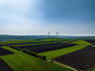 Fototapeta na wymiar aerial view of well-maintained plowed fields during spring with two wind turbines on horizon