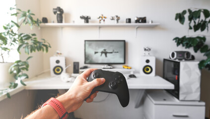 Close-up of male hands holding white wireless gamepad against white computer dream desk.