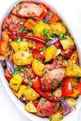 Baked spicy turkey ragout with potatoes, paprika, red onion, herbs and spices in oval ceramic baking dish, white table background, top view close-up