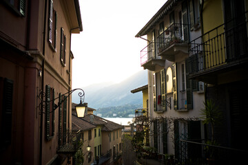 Lake Como from the shore of the town of Bellagio. View of the Alps mountains, buildings and a passenger ferry. Sunset