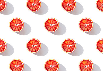 Creative pattern made with half of blood orange on white background with shadow. Summer fruit and vitamin concept. Minimal style. Top view