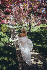 Beautiful woman runs in the garden. Bride with flowers.