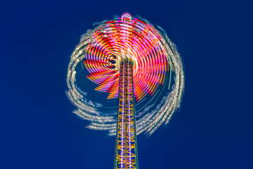 Merry-go-round or chairoplane with colorful led illumination at evening blue hour twilight....