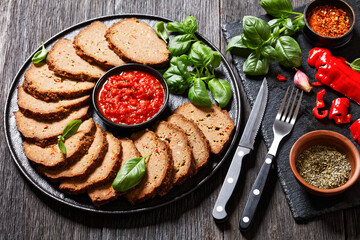 italian meatloaf cut in slices on black plate