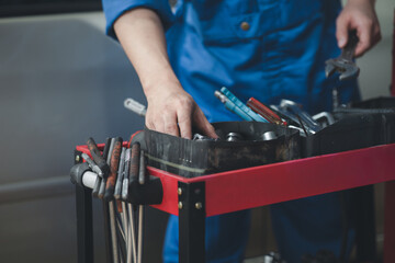 Professional car mechanics searching for auto repair tools in tool racks, all kinds of auto specialists, expert auto repair and accredited auto repair centers.