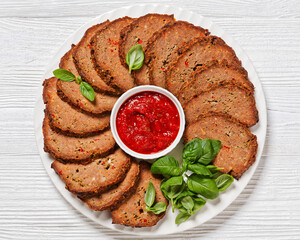 italian meatloaf cut in slices on white plate
