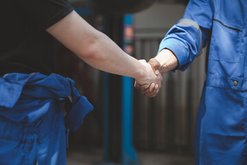 Two professional auto mechanics shaking hands, all kinds of car specialists, expert auto repair and...