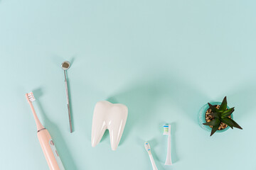 White healthy tooth model, dental mirror and electric toothbrush with different toothbrush heads on...