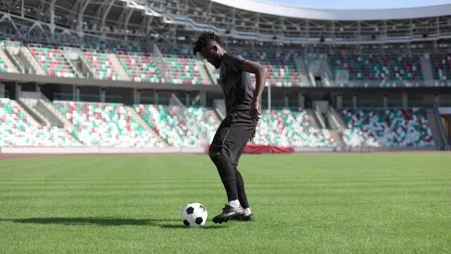 Young black soccer player kicking and kicking a soccer ball in the stadium