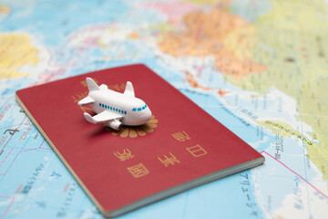 地図の上に置かれた日本のパスポートと玩具の飛行機