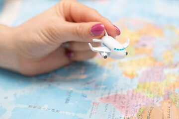 飛行機の玩具を持った女性の手と世界地図
