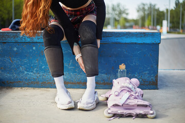 Young skater girl putting on protective shin guards and knee pads for skating. Unrecognizable...