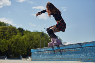 Young roller blader grinding on a ledge in a skatepark. Cool female skater wearing modern aggressive skates performing a backside full torque grind outdoor