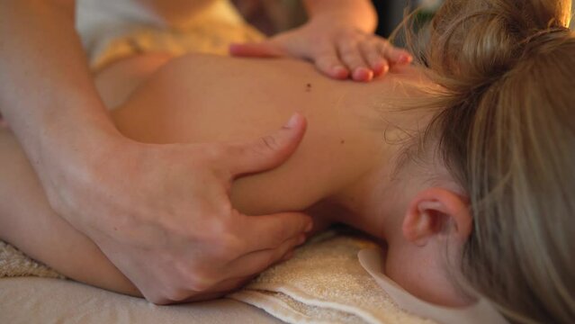 Body massage treatment. Woman having massage in the spa salon. Masseur working on his back and shoulders.	
